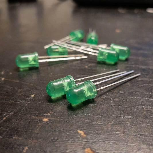 5mm green LEDs on wooden workbench showing translucent lens and metal leads