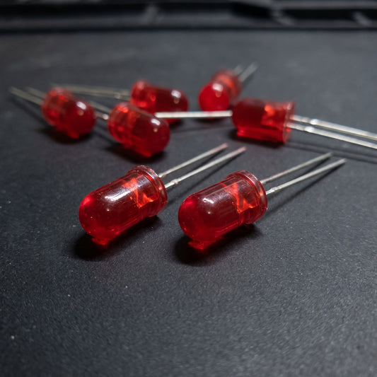 5mm red LEDs scattered on workbench showing translucent lens and metal leads