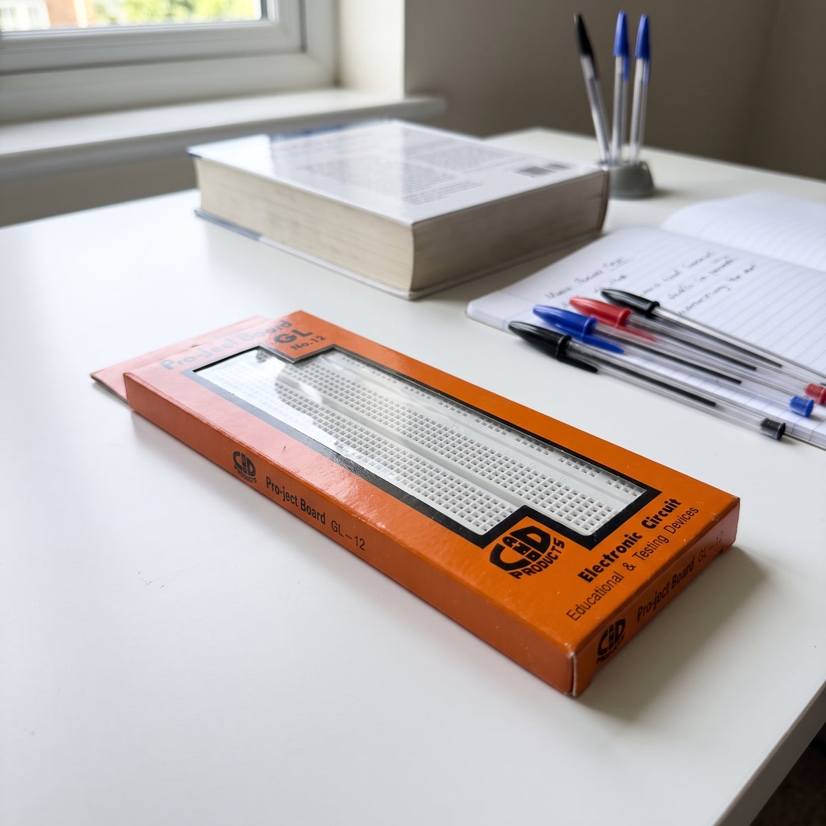 GL-12 breadboard product view in orange packaging showing white solderless breadboard